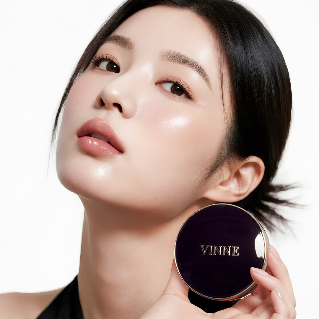 A professional beauty model with flawless, glowing skin holding the VINNE Cushion Foundation compact. This premium K-beauty cushion provides a natural radiant finish and long-lasting hydration for a perfect complexion.