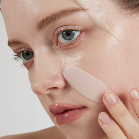 A glowing, confident woman with flawless skin, standing next to the VINNE Collagen Mask 12-pack, the ultimate home care investment.