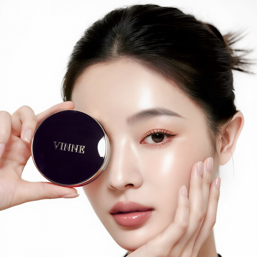 "A beauty model with radiant glass skin holding the VINNE Cushion Foundation compact. This premium K-beauty foundation provides a flawless, glowing complexion with high coverage and long-lasting hydration.